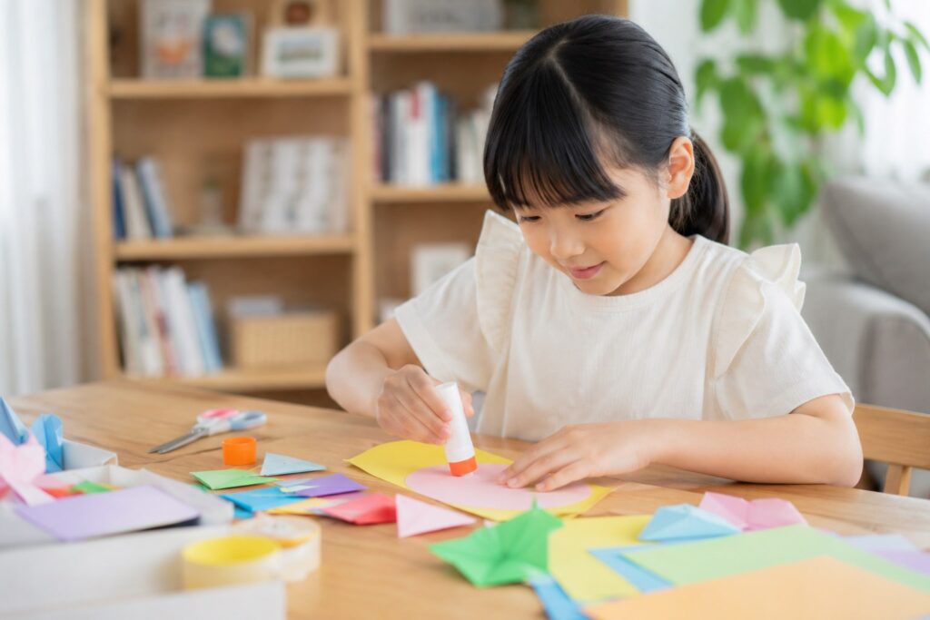 家で折り紙とノリで工作する子供