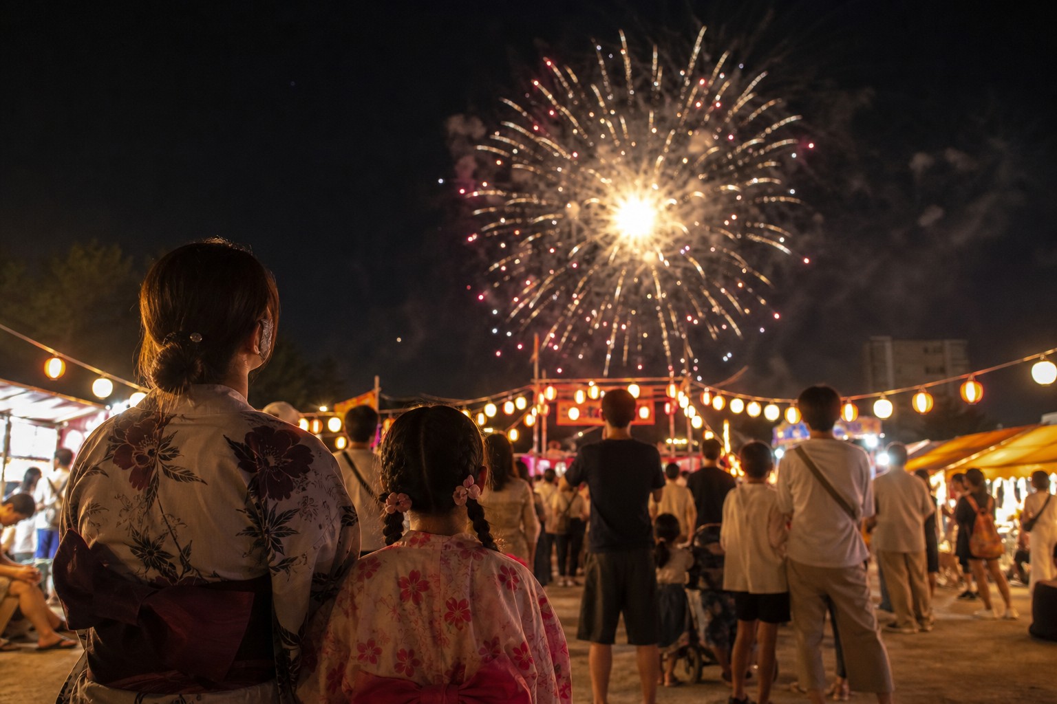 地域の夏祭り会場で短時間の花火を楽しむ親子